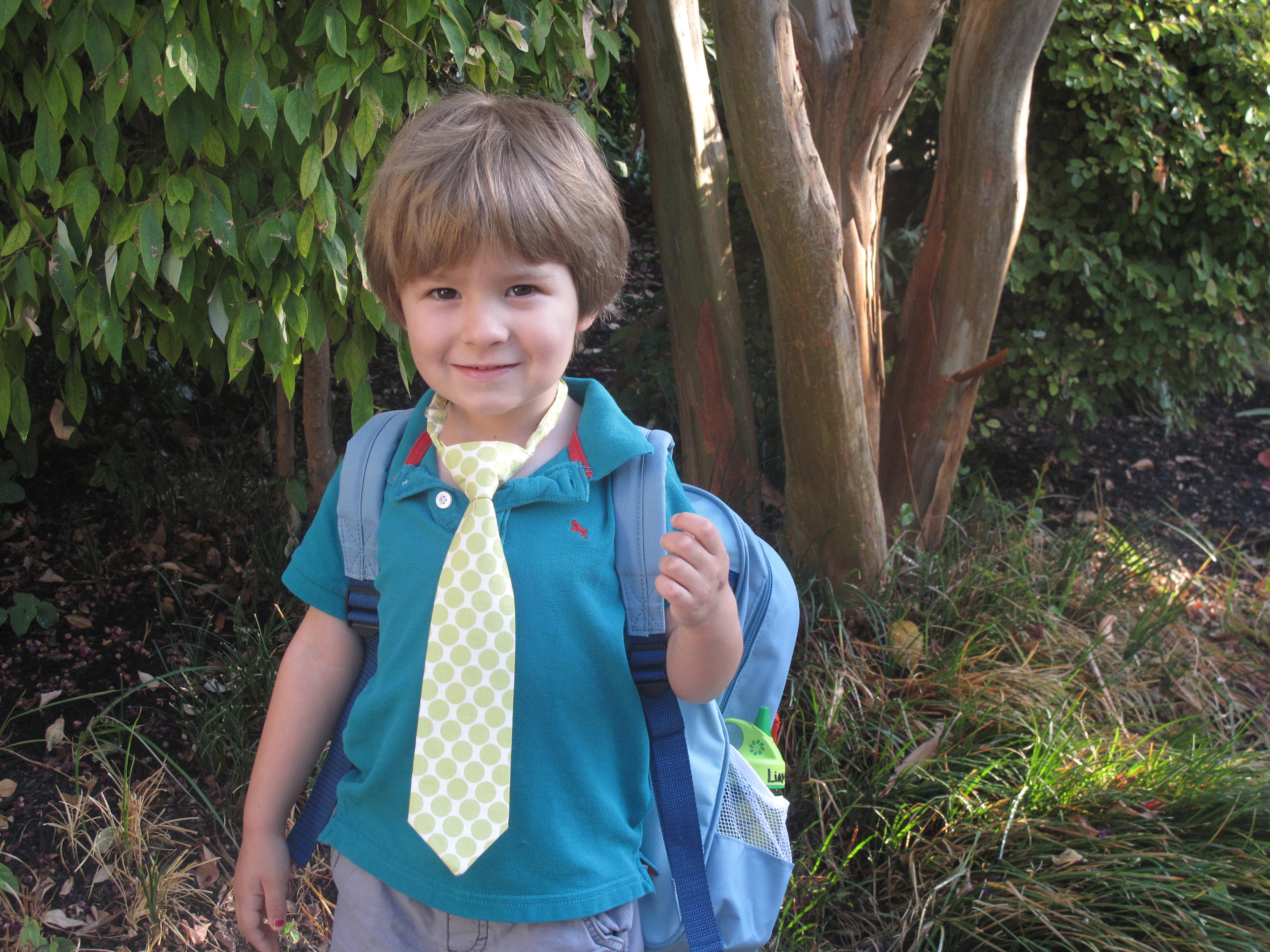 A boy with a backpack and a tie.