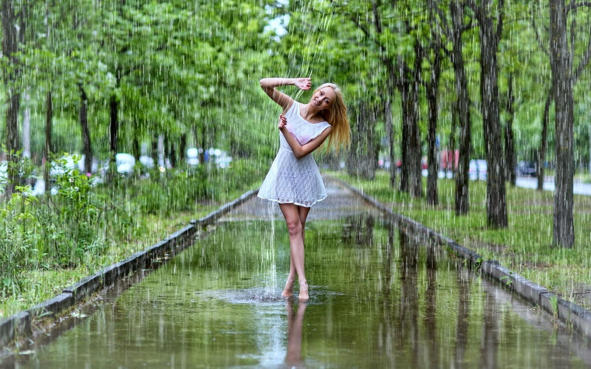 Девушка в белом платье гуляет под дождем