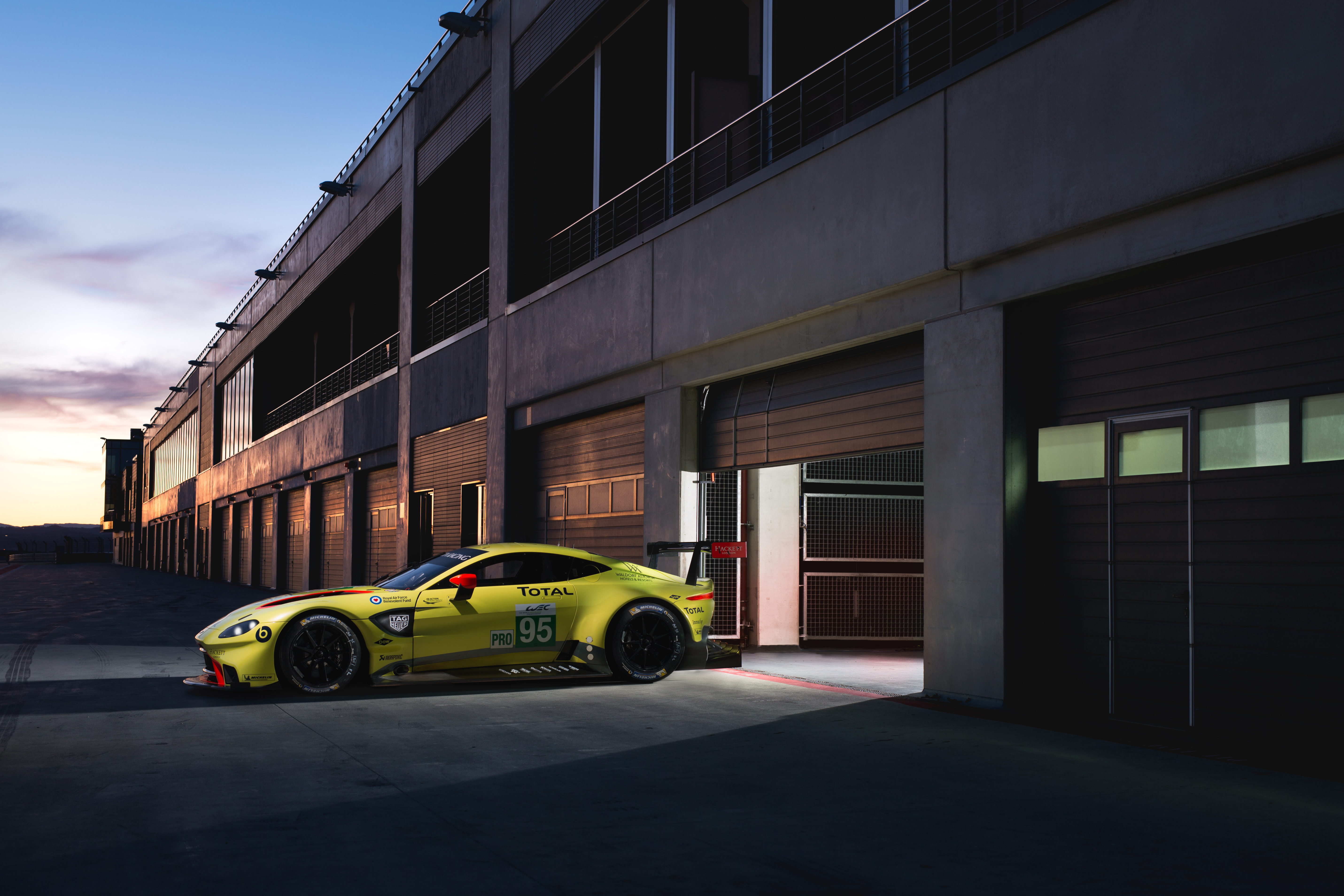 Aston Martin Vantage желтого цвета стоит у гаража