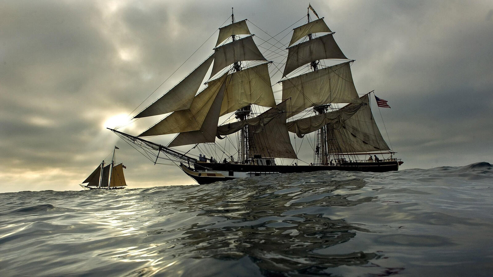 Бесплатное фото Большой корабль с белыми парусами на закате