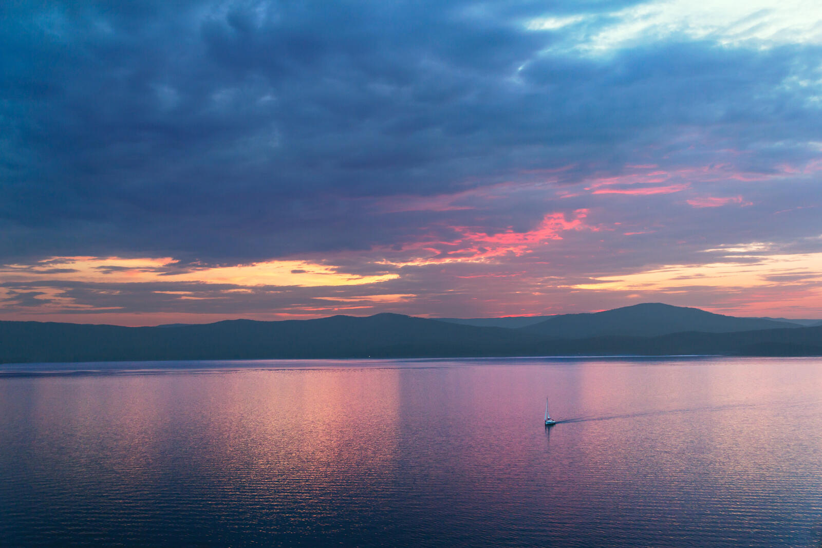 Бесплатное фото Одинокий парусник среди огромного озера