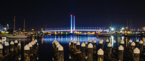 Вид на подсвеченный мост через реку в ночи