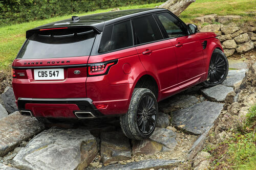 Range Rover красного цвета едет по камням