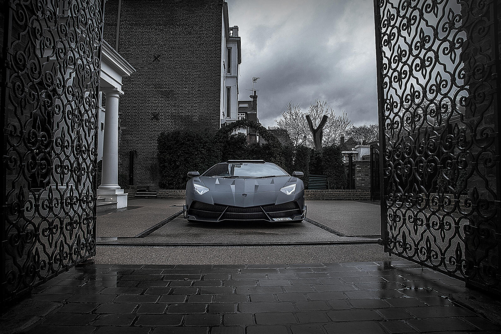 Free photo A matte black Lamborghini pulls into the courtyard of the mansion.