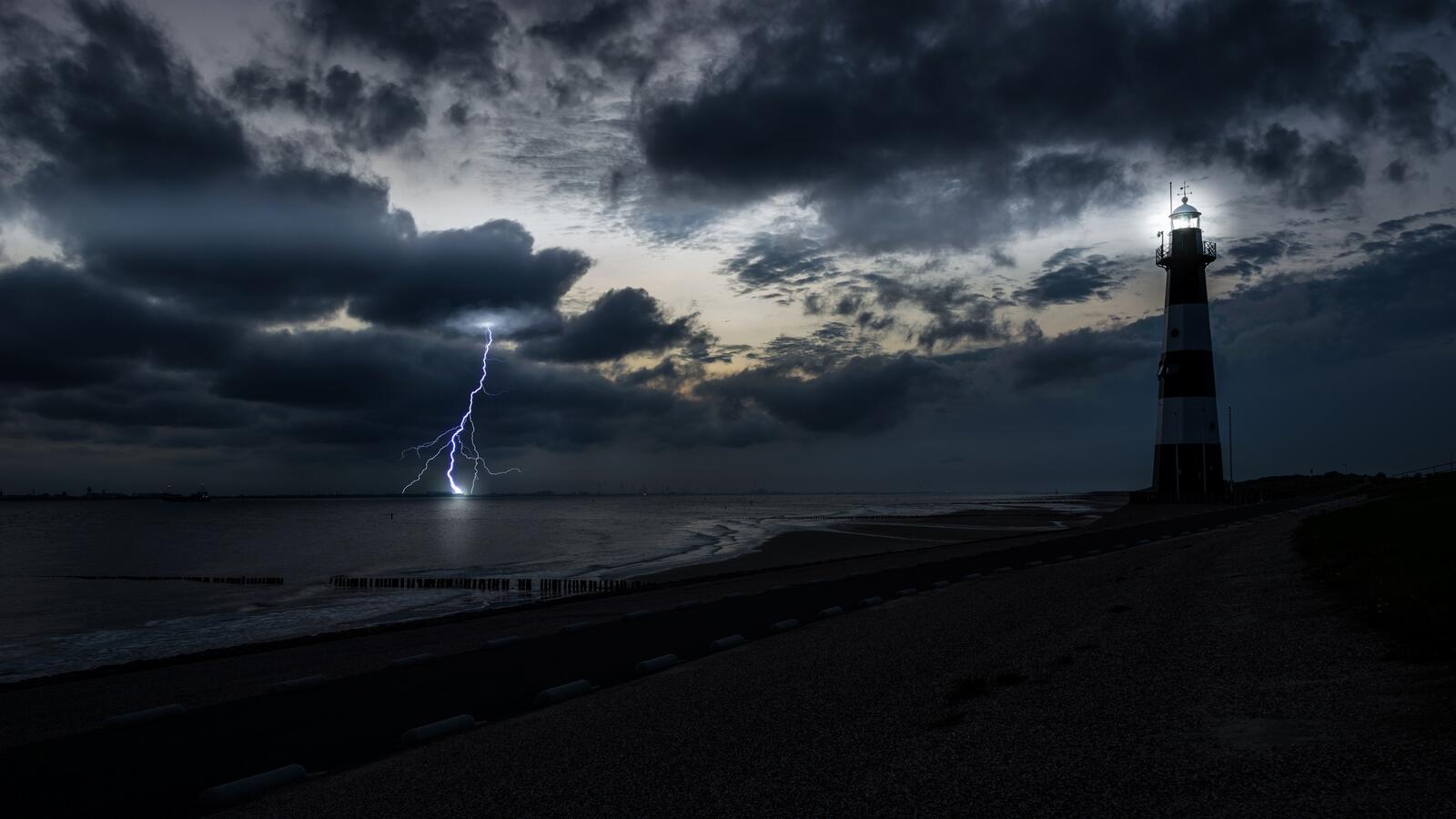 Бесплатное фото Ночная молния во время шторма рядом с маяком