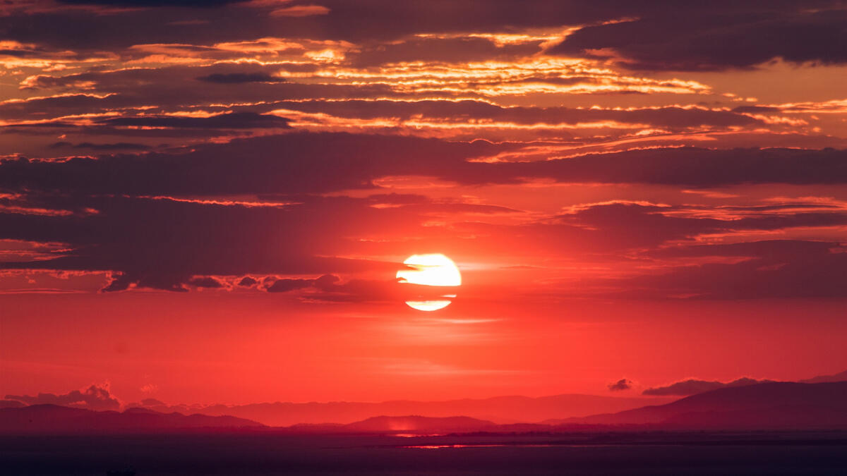 A red sun in a cloudy sky