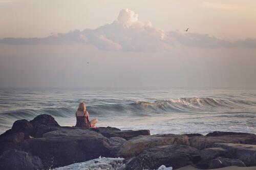 A girl admires the sea waves sitting by the sea