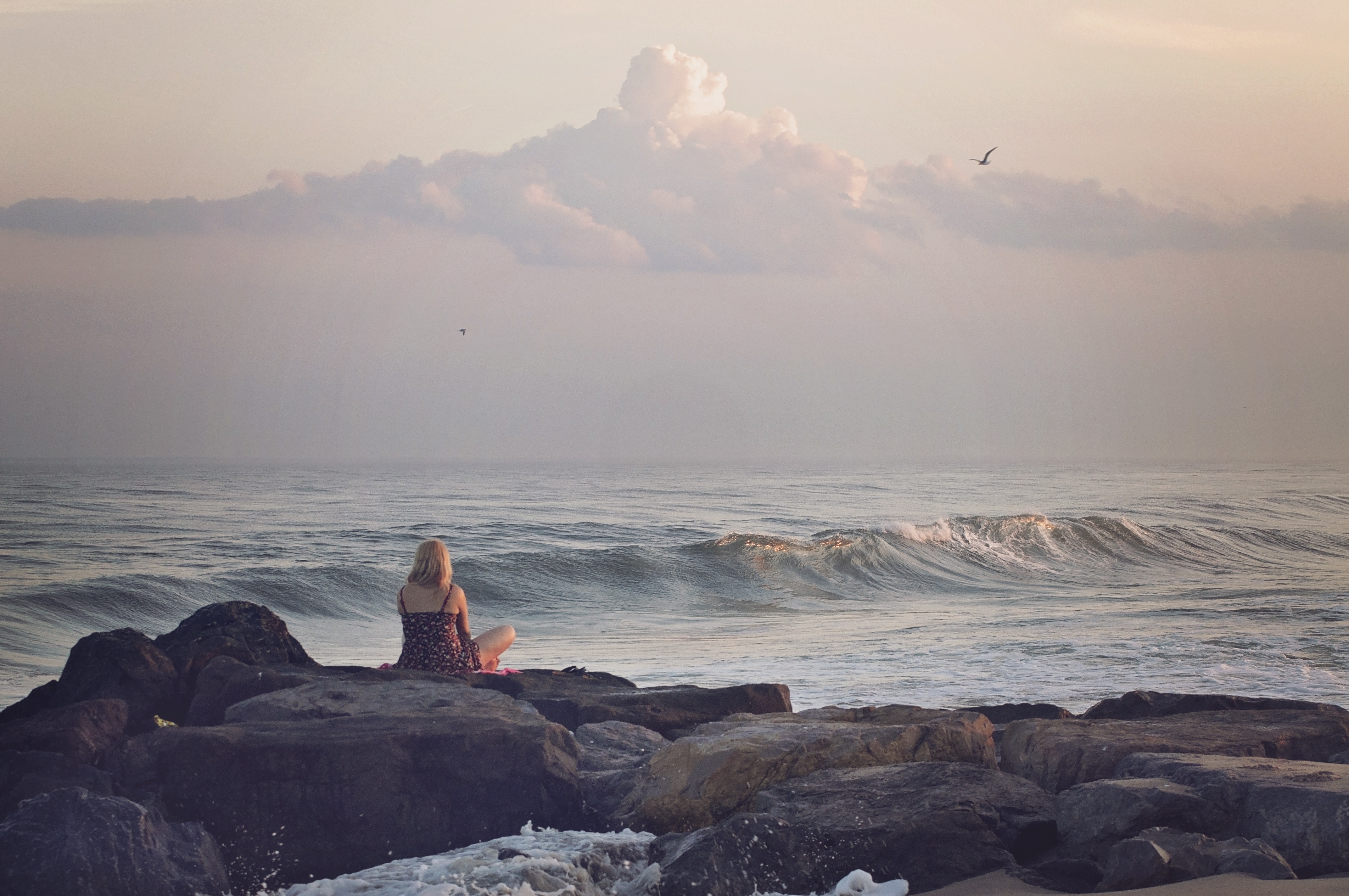 Бесплатное фото Девушка любуется морскими волнами сидя у моря