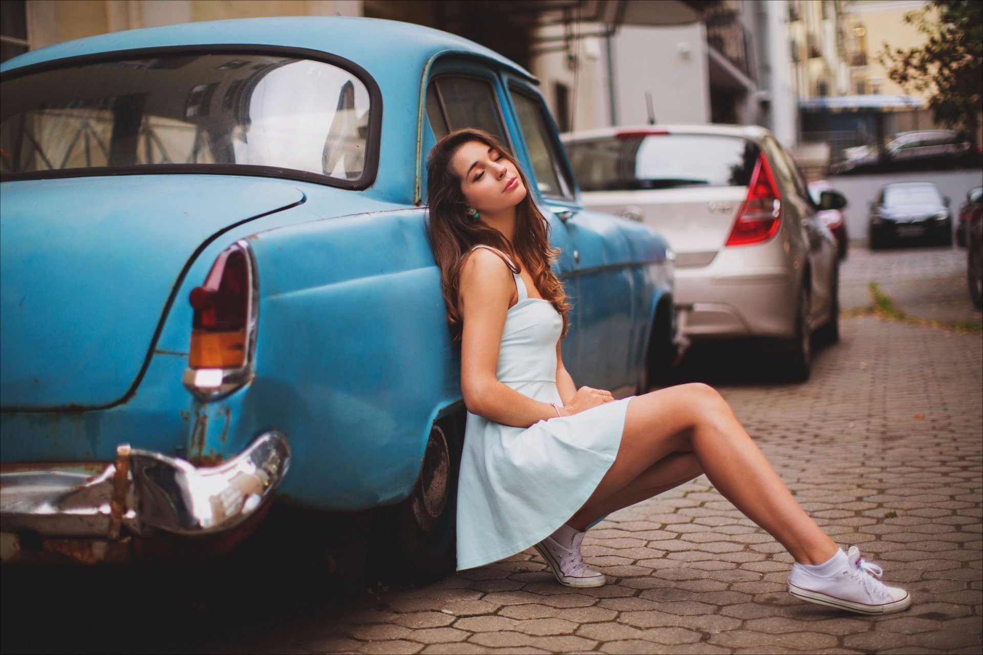 A girl in front of a blue vintage car