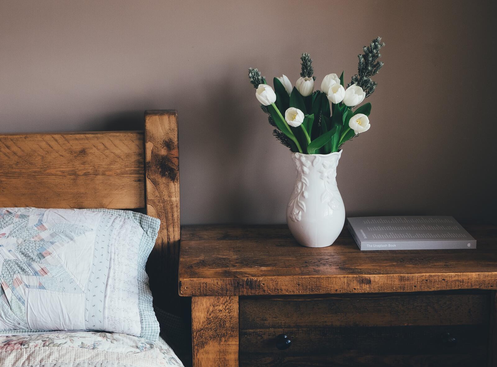 Бесплатное фото Букет с белыми тюльпанами в вазе у кровати