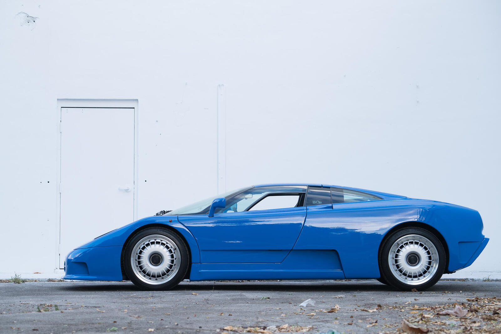 Free photo Blue bugatti eb110 against a white wall