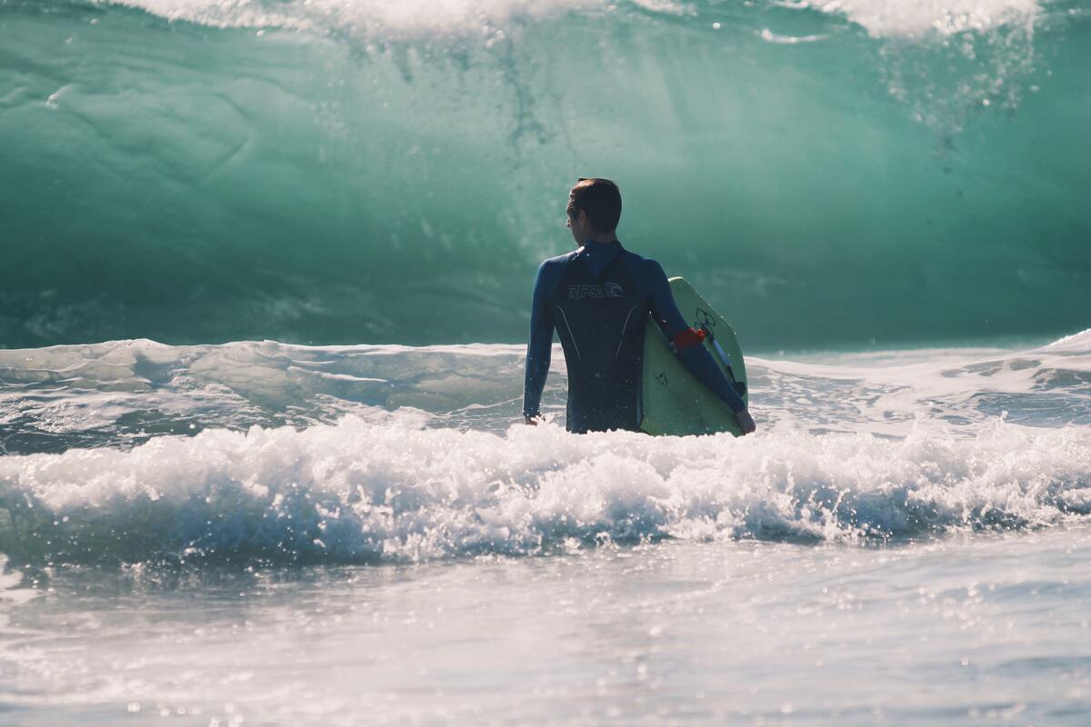 Мужчина серфингист на фоне большой волны