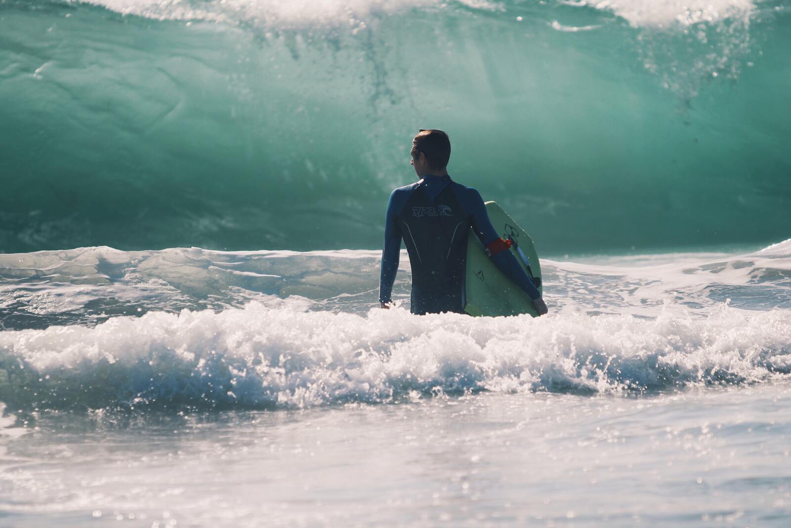 Бесплатное фото Мужчина серфингист на фоне большой волны