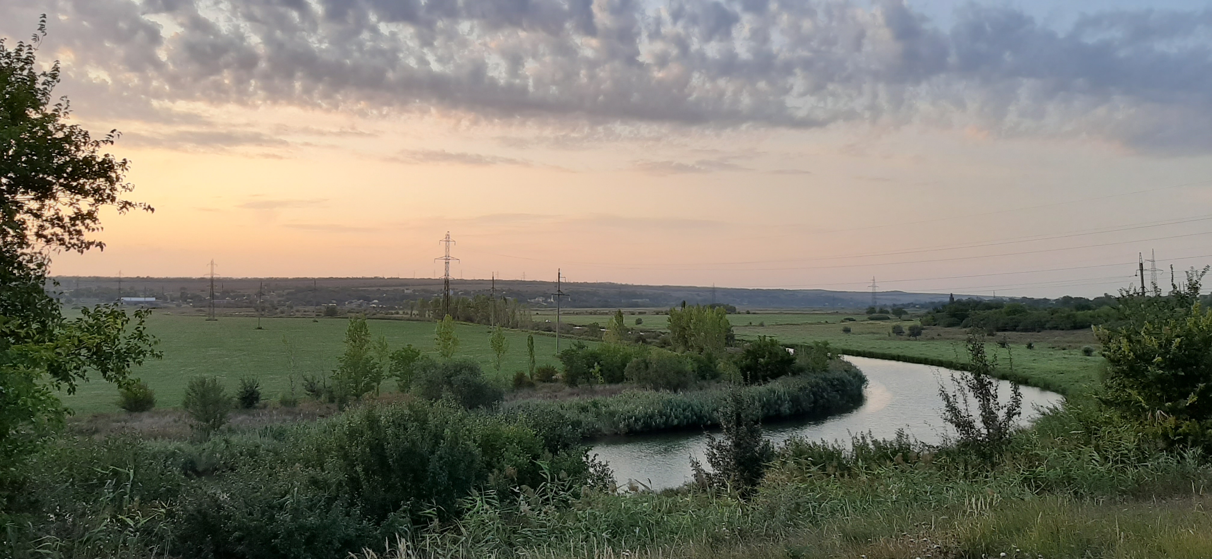 Sunset on the river and a green field