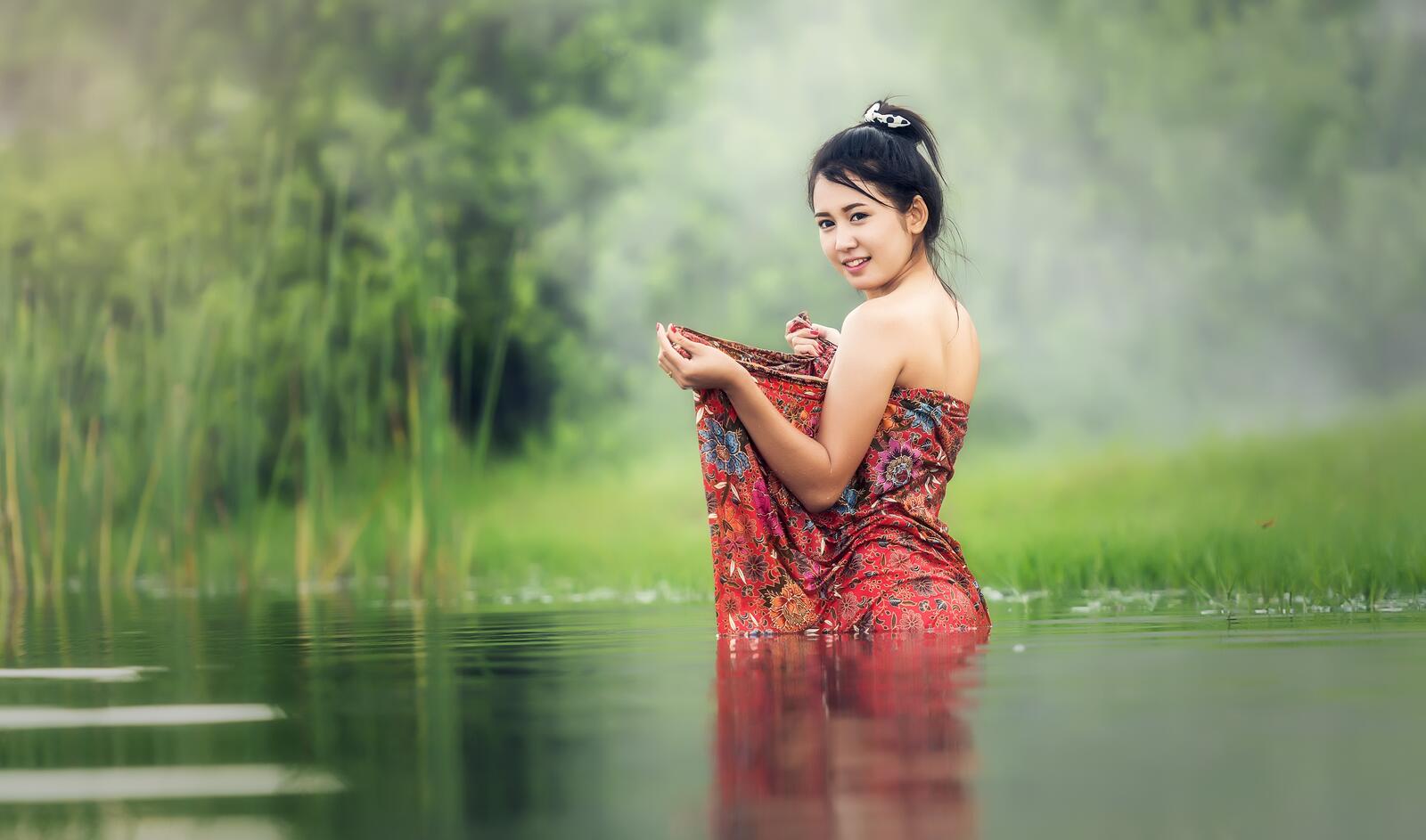 Free photo Asian woman in a red dress standing in the water
