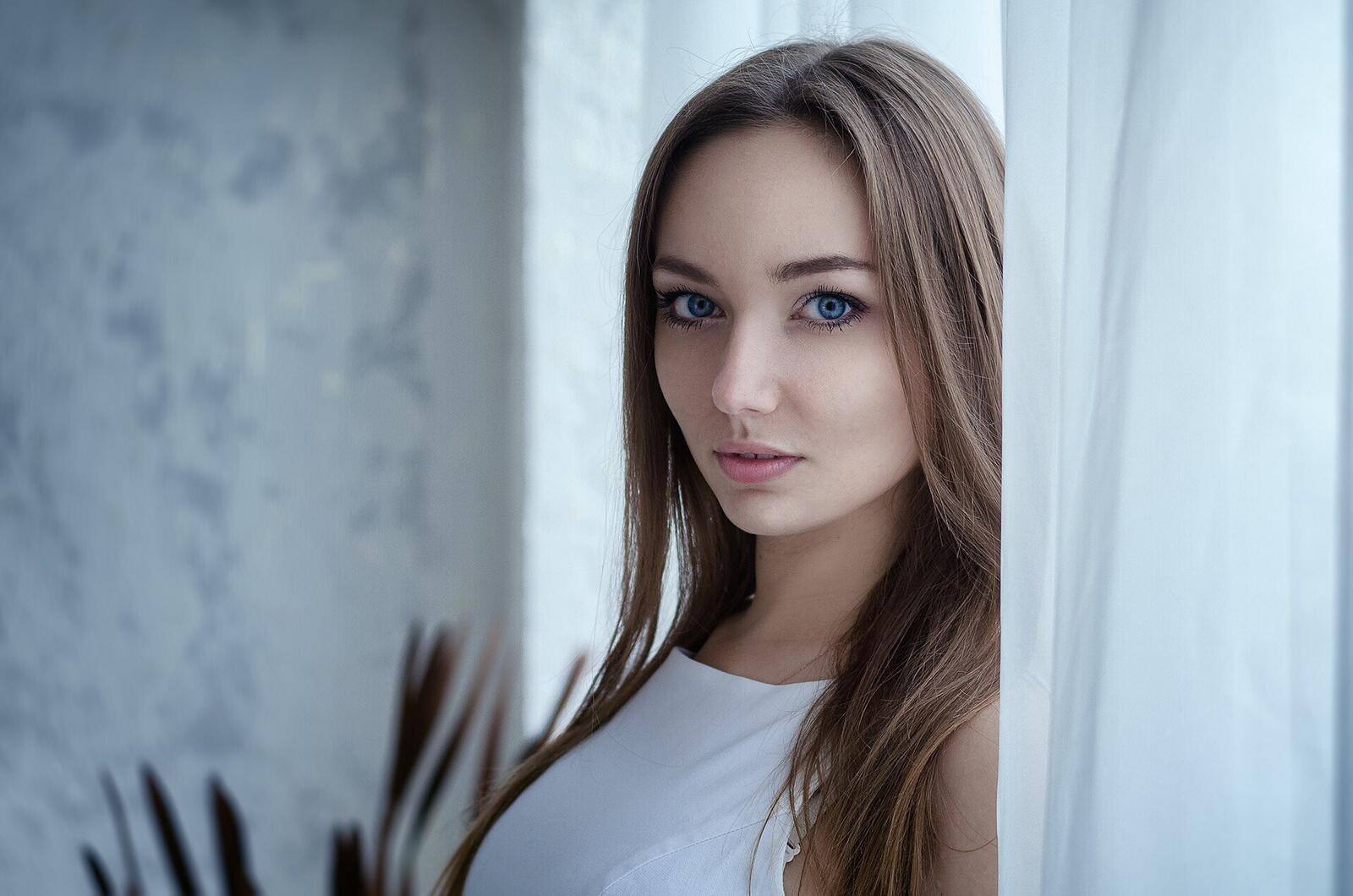 Free photo Blue-eyed brown-haired girl standing on the curtain