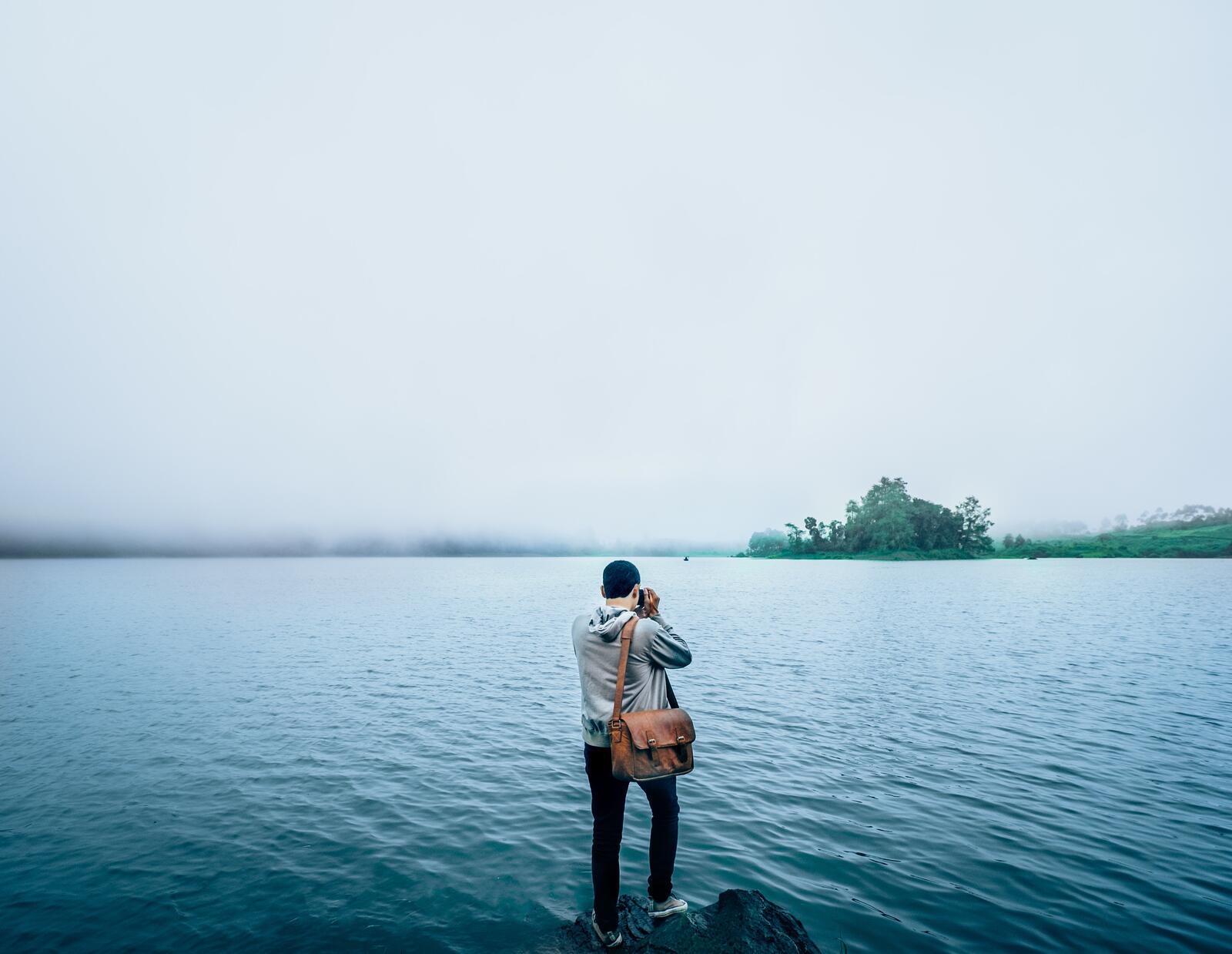 Бесплатное фото Мужчина фотографирует утреннее туманное озеро