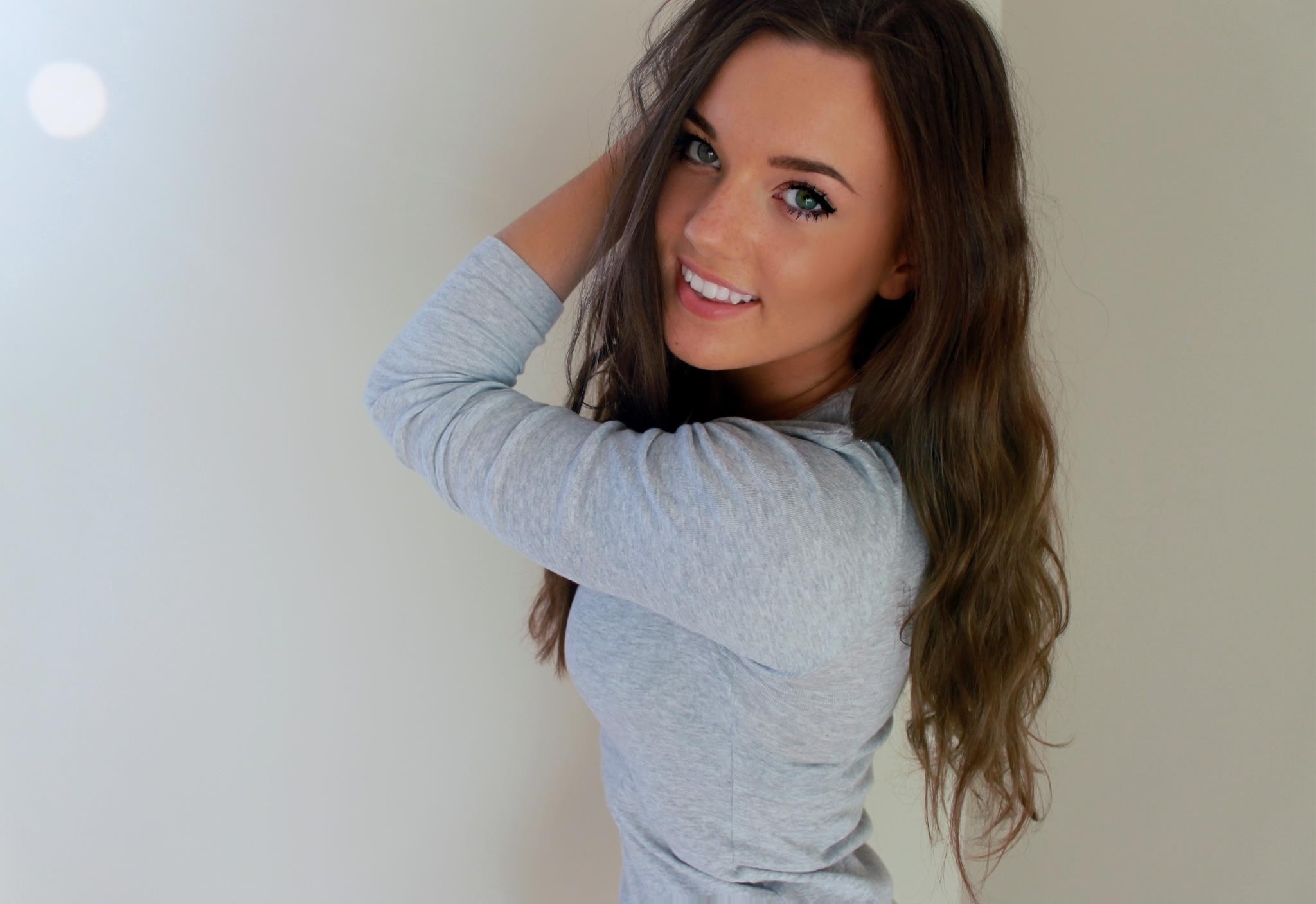 Model smiling against a gray wall