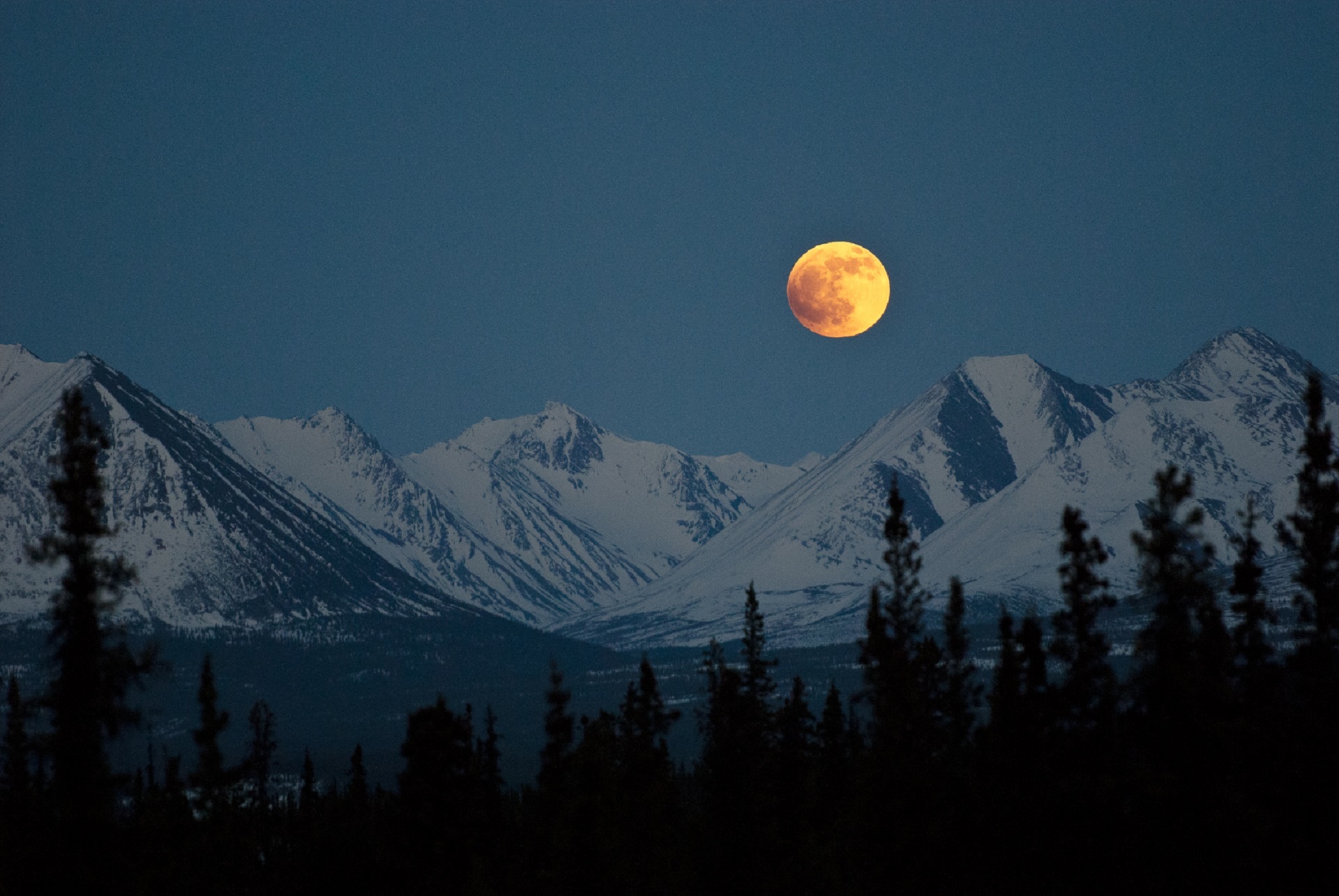 Free photo The big moon over the snowy mountains