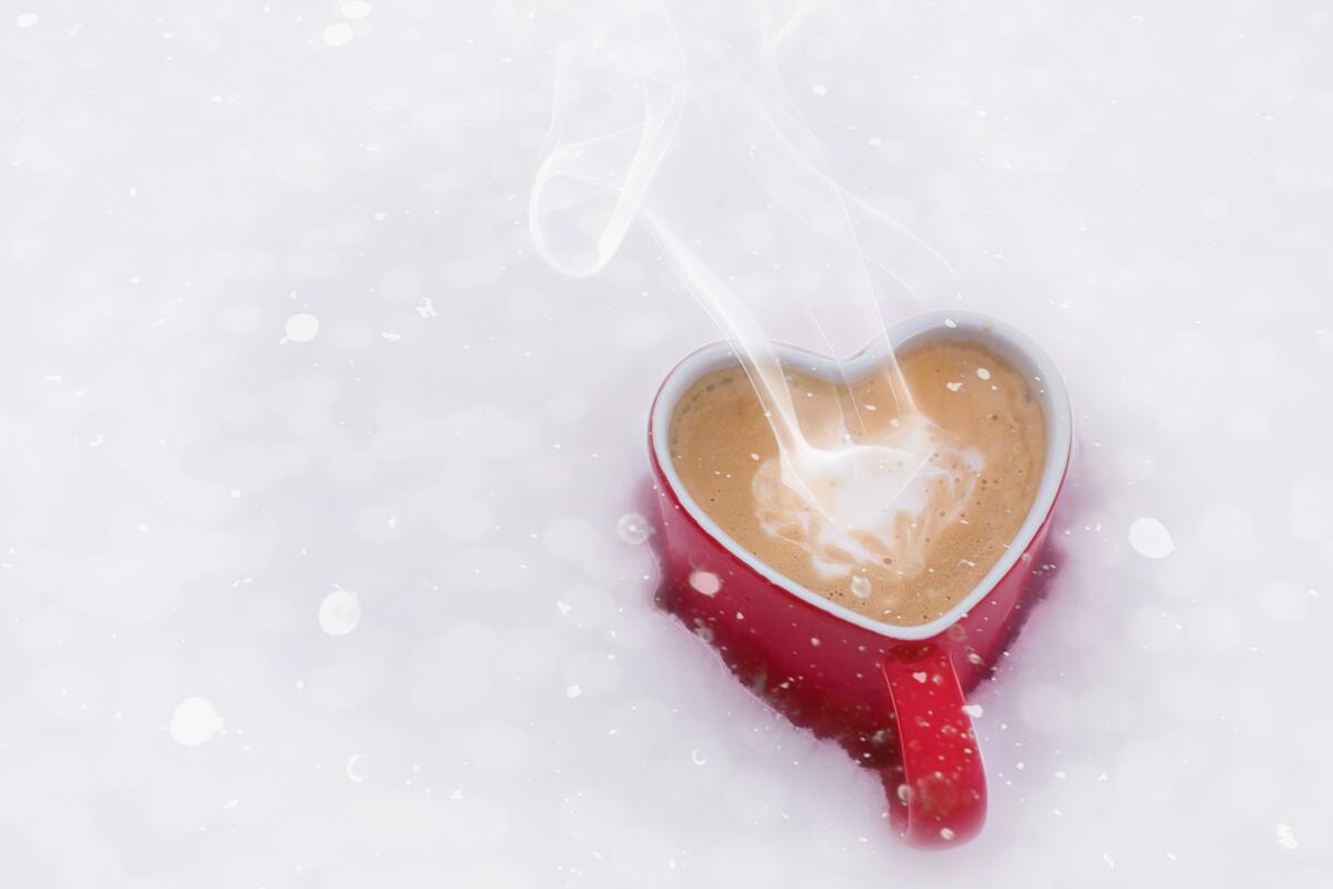 Red coffee mug in the snow on Valentine`s Day