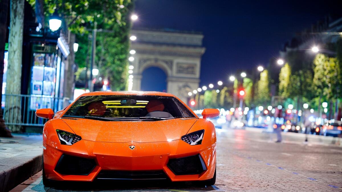 Orange Lamborghini Aventador with the city as a backdrop.