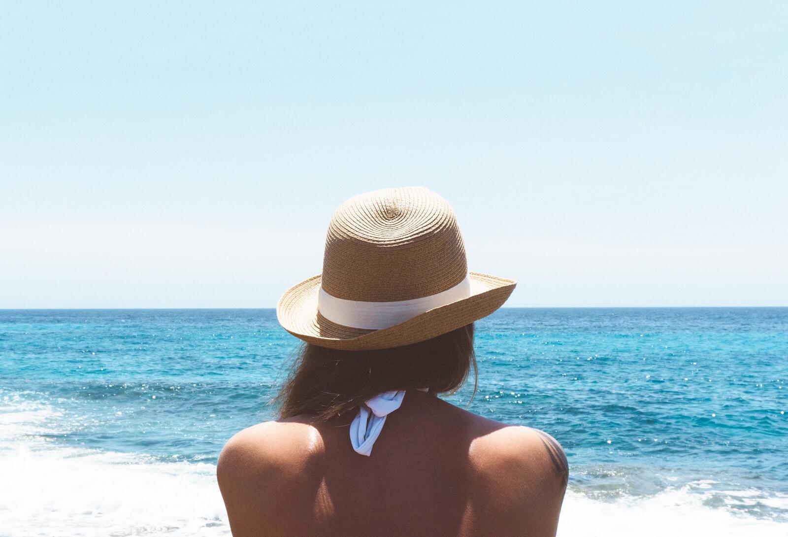 Бесплатное фото Женщина в шляпе смотрит вдаль моря