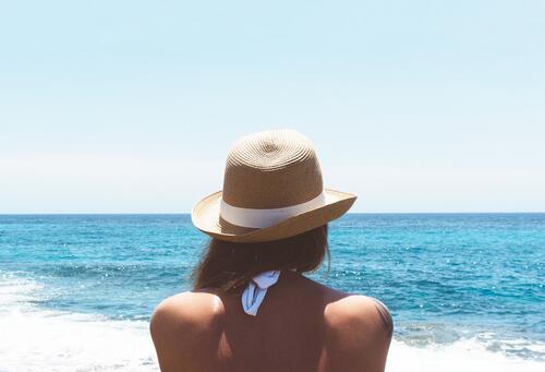 Женщина в шляпе смотрит вдаль моря