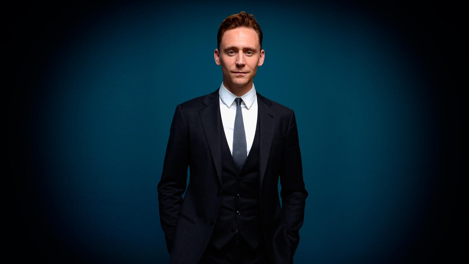 Free photo Tom Hiddleston in a suit against a dark blue background