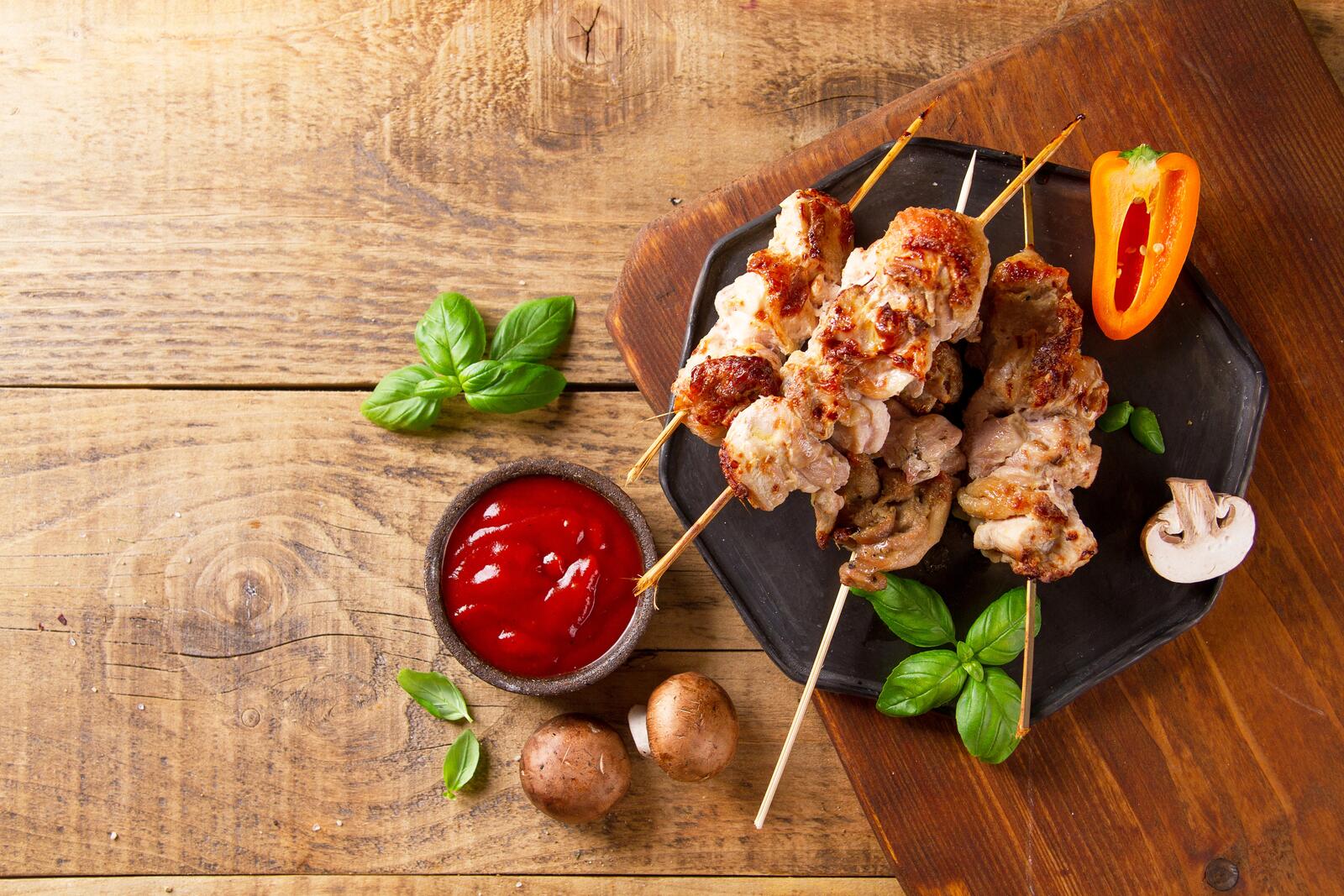Free photo Delicious meat on skewers with mushrooms and red sauce