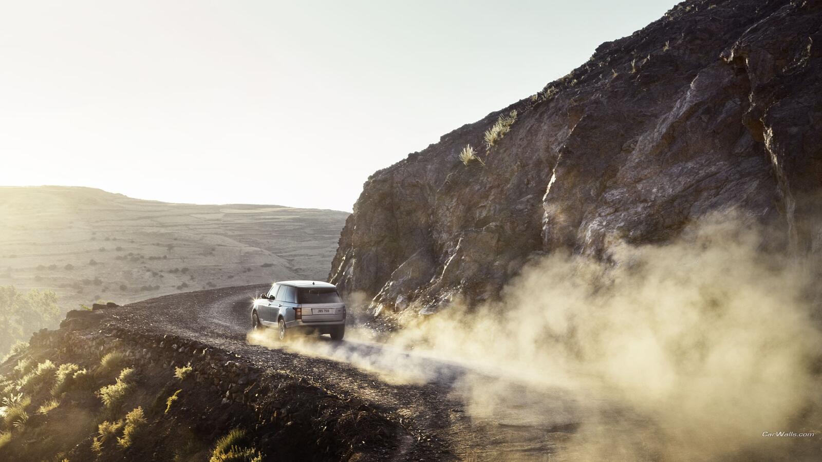 Free photo Range Rover rides through the dust in the mountains