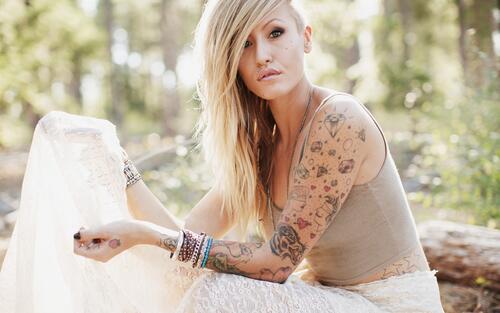 Blonde girl with a tattoo on her arm.