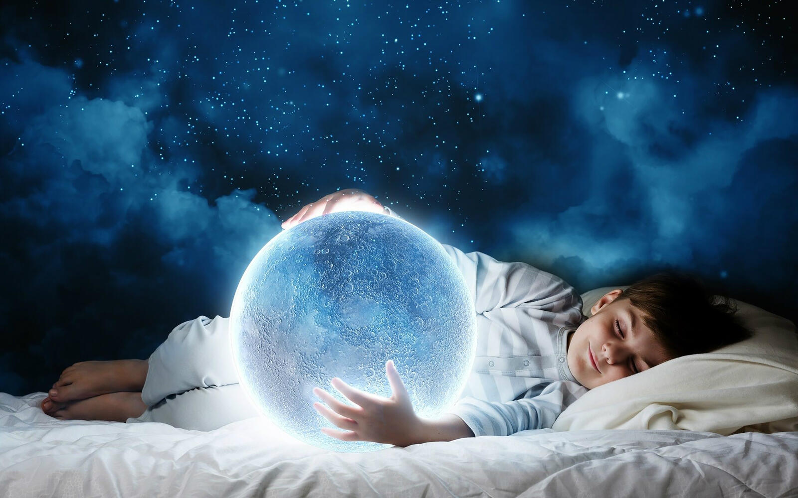 Free photo A boy sleeps with a nightlight in the form of a glowing moon.