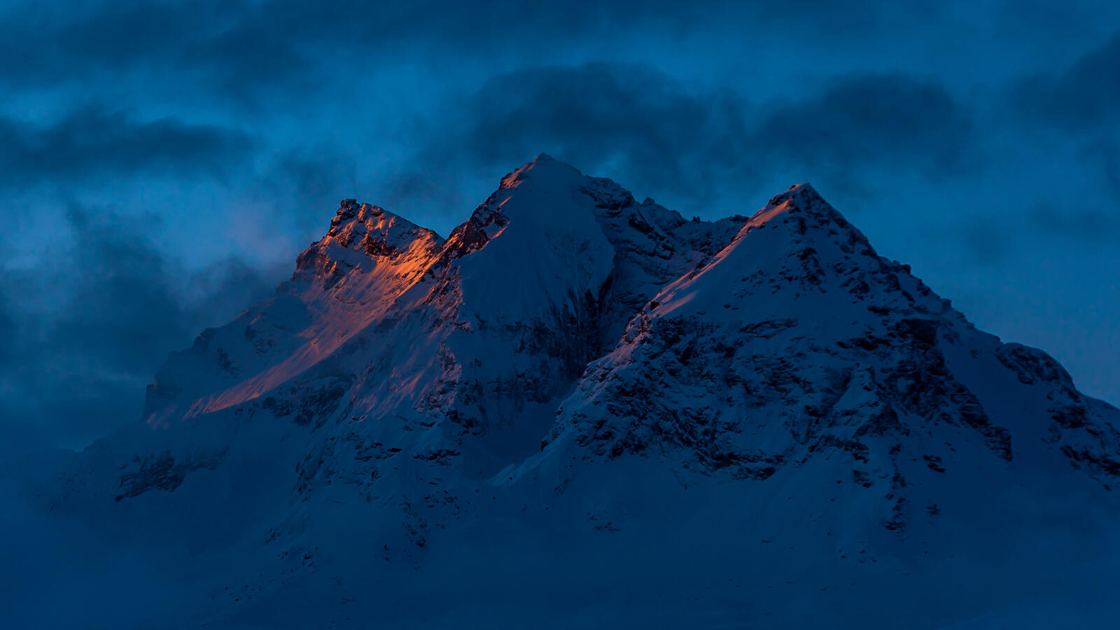 Бесплатное фото Туманная снежная гора с холмами освещенными закатом солнца