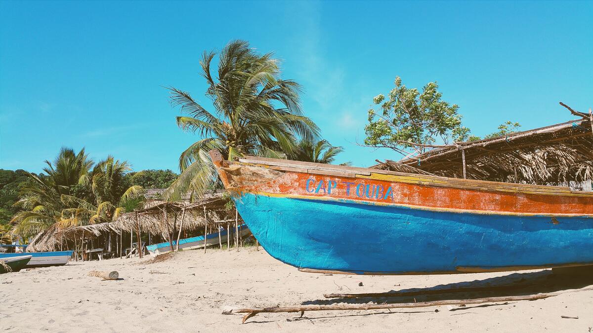 An old abandoned boat on a beach with palm trees