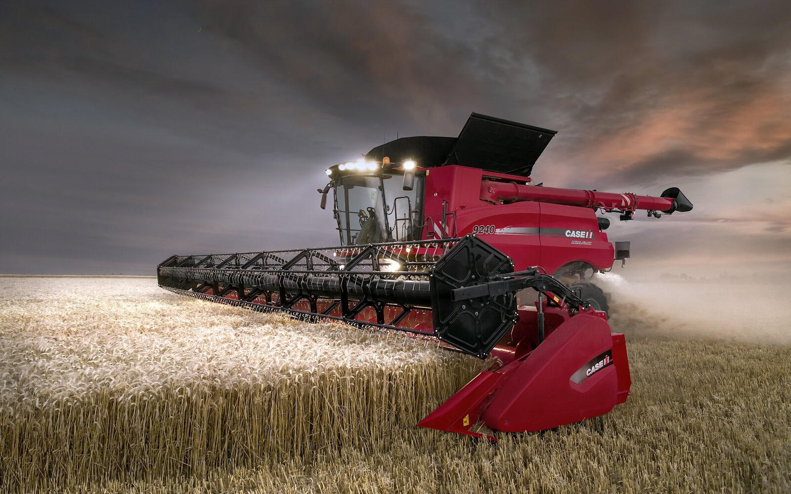 Бесплатное фото Красный комбайн собирает урожай с большого поля