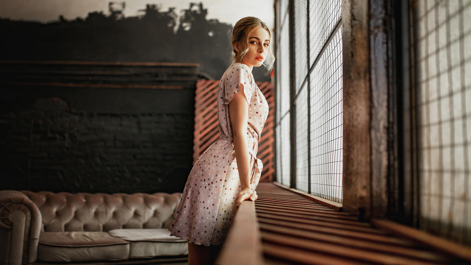 Бесплатное фото Молодая девушка в пятнистом платье стоит у окна