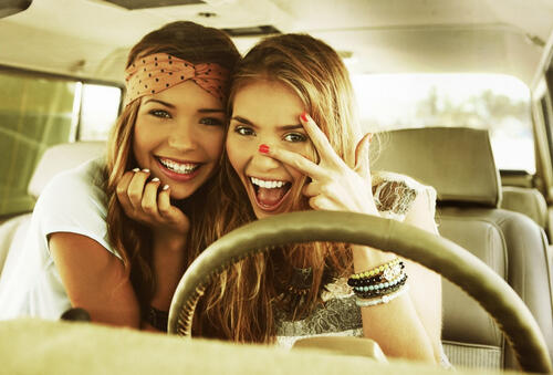 Two girlfriends pose for the camera in the car