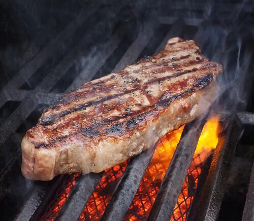 Steak meat is cooked over an open flame