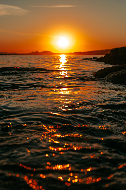 The sunset is reflected in the ripples of the sea