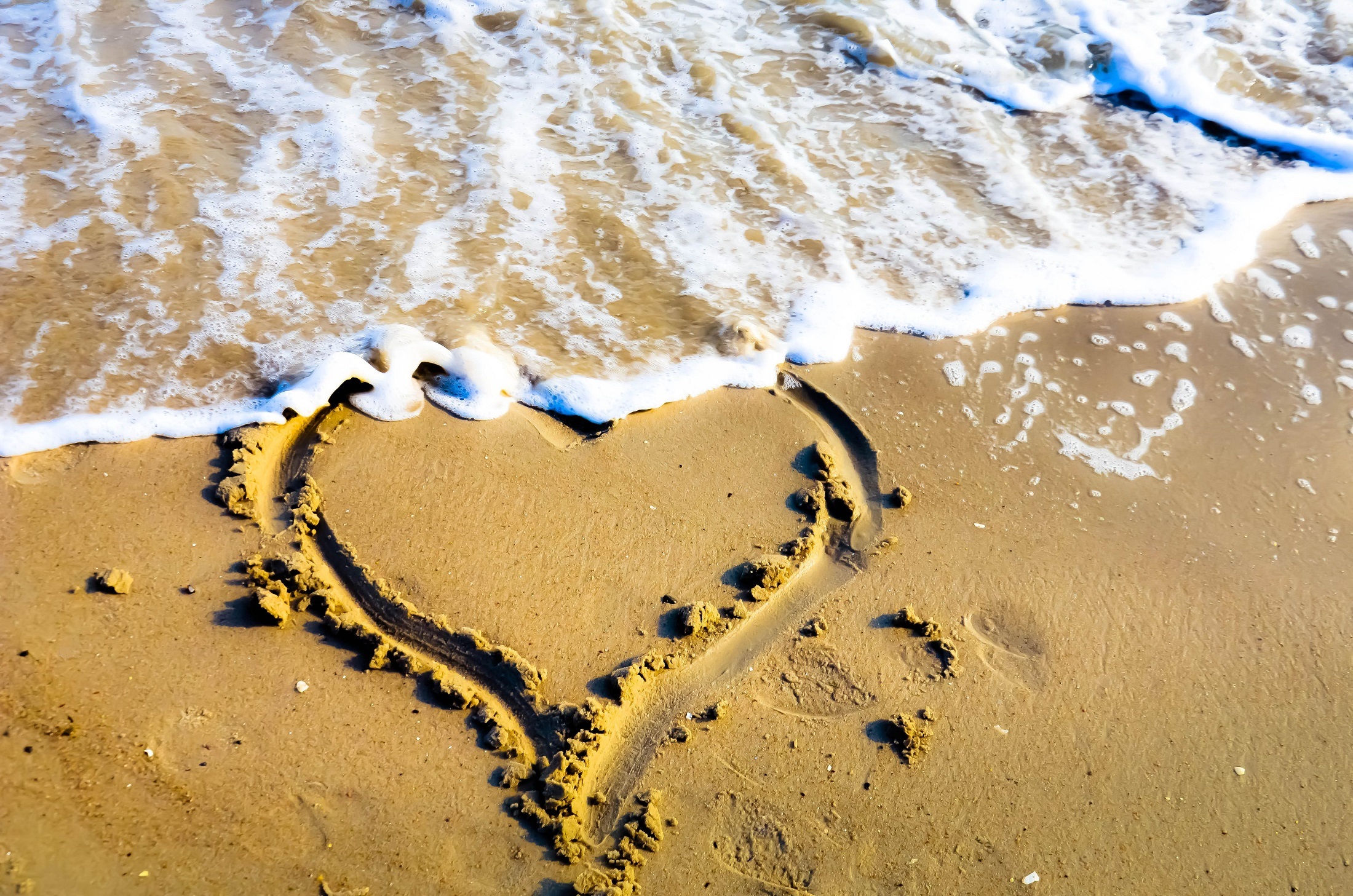A heart drawn on the shore of a sandy beach