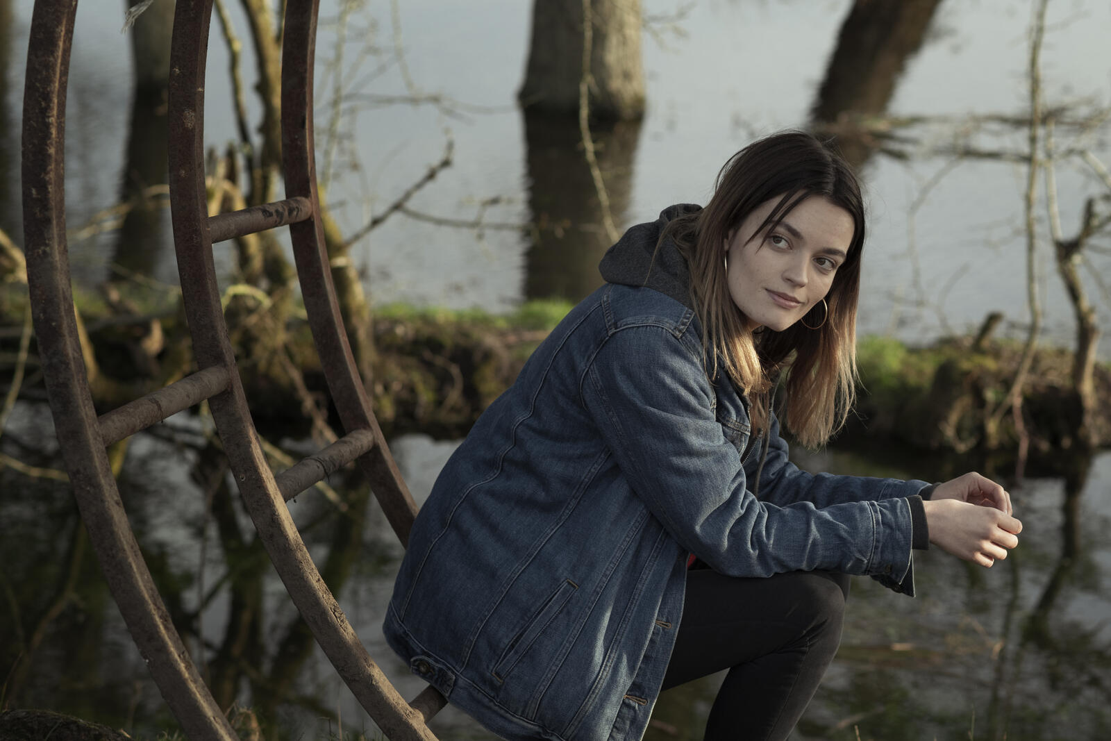 Бесплатное фото Эмма Маккей сидит на железной конструкции в джинсовой куртке