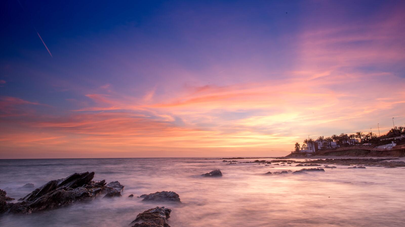 Бесплатное фото Пляжные дома на берегу моря при закате дня и падающем метеорите в небе