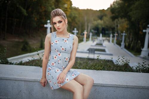 Блондинка сидит в платье на бетонной плите