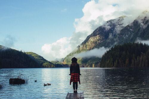 Девочка стоит на мостике у озера