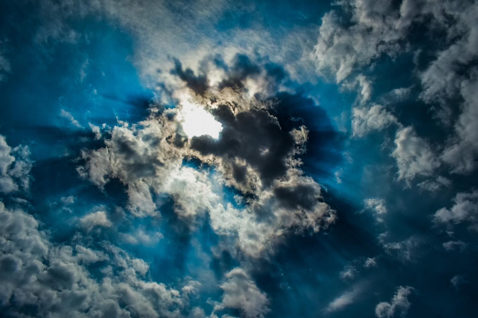 Бесплатное фото Голубое небо с облаками через которые пробиваются лучи солнца