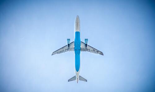 An airplane flies against the blue sky