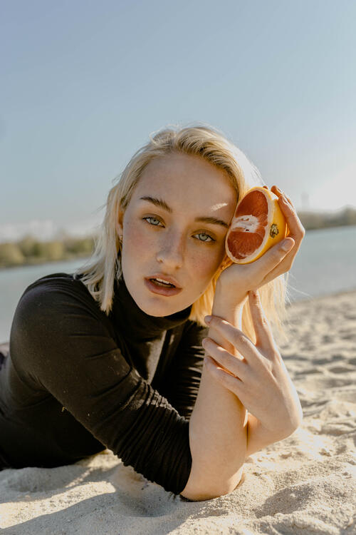 Pretty blonde girl in black turtleneck with grapefruit