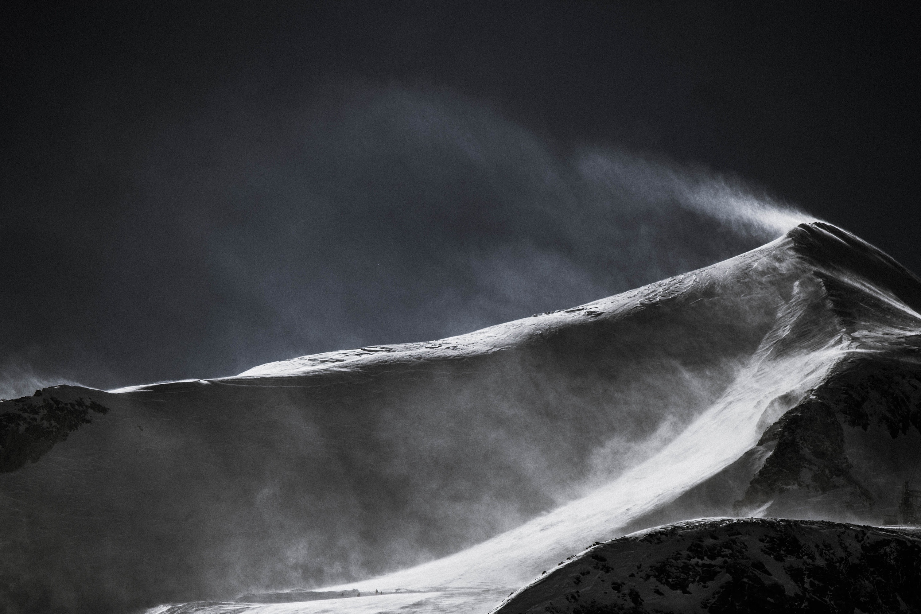 Бесплатное фото Сильный ветер сдувает снег с макушки горы