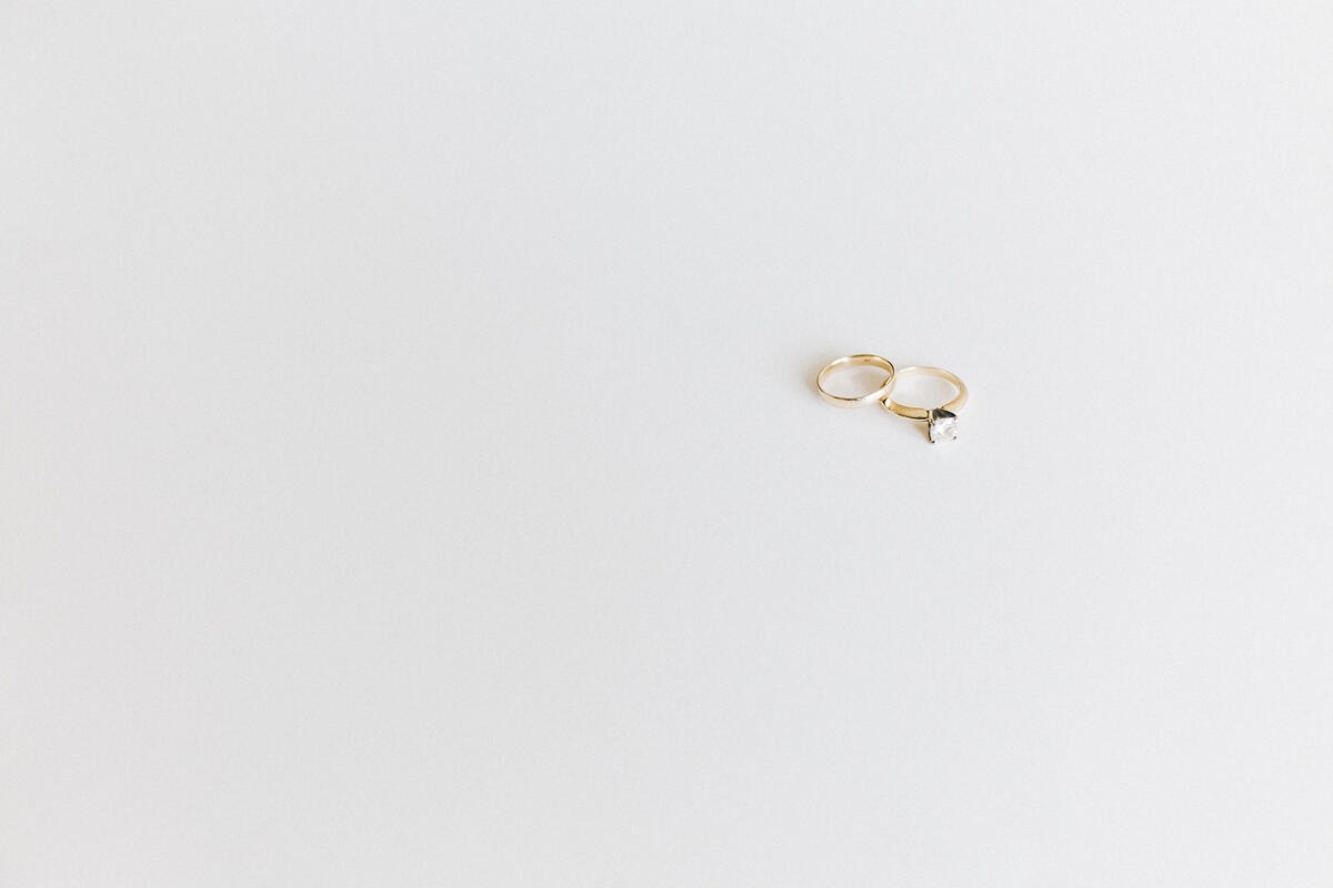 Two gold wedding rings on a light gray background