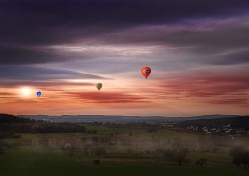 Balloons fly in the sky at sunset